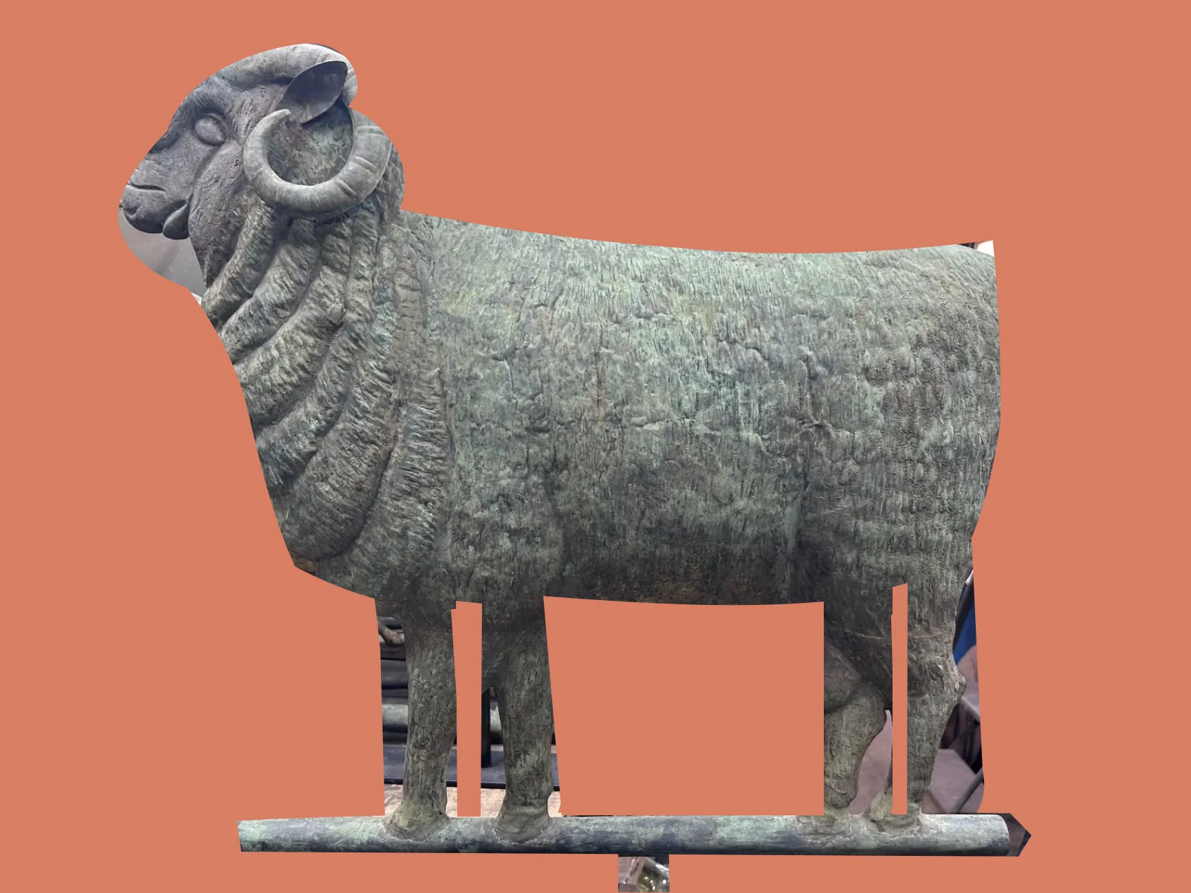 Front three-quarter view of a copper full-bodied sheep weathervane with its support, isolated on a warm salmon background