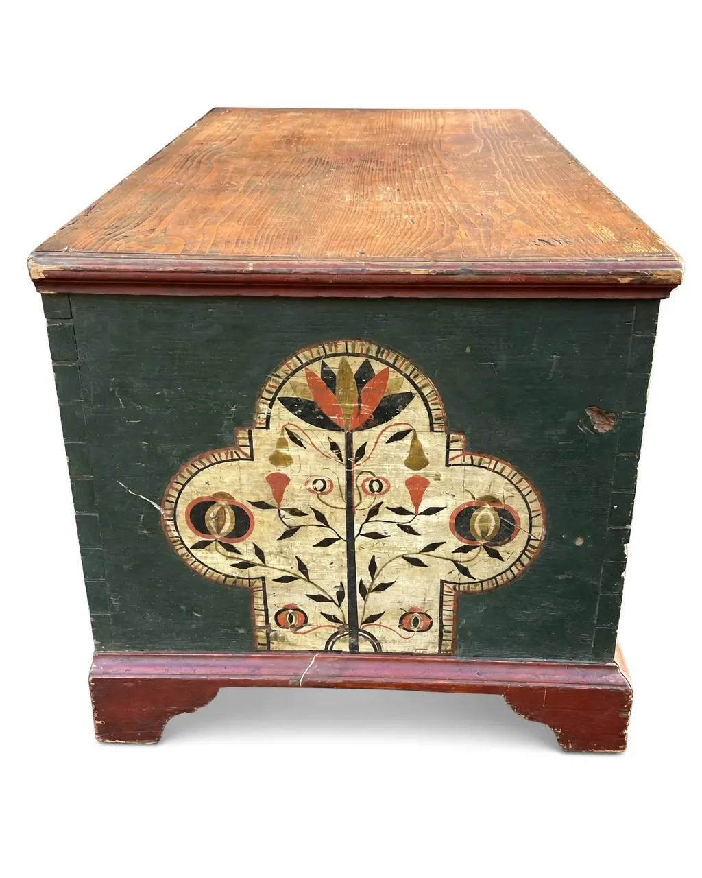 Tole-painted wooden blanket chest with dark green paint, a natural wood lid, floral decoration, and distressed red-painted bracket feet isolated on a white background